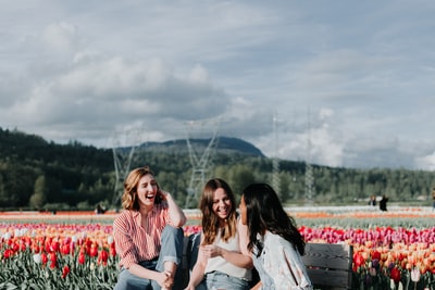 3女性坐在长椅上附近的鲜花

